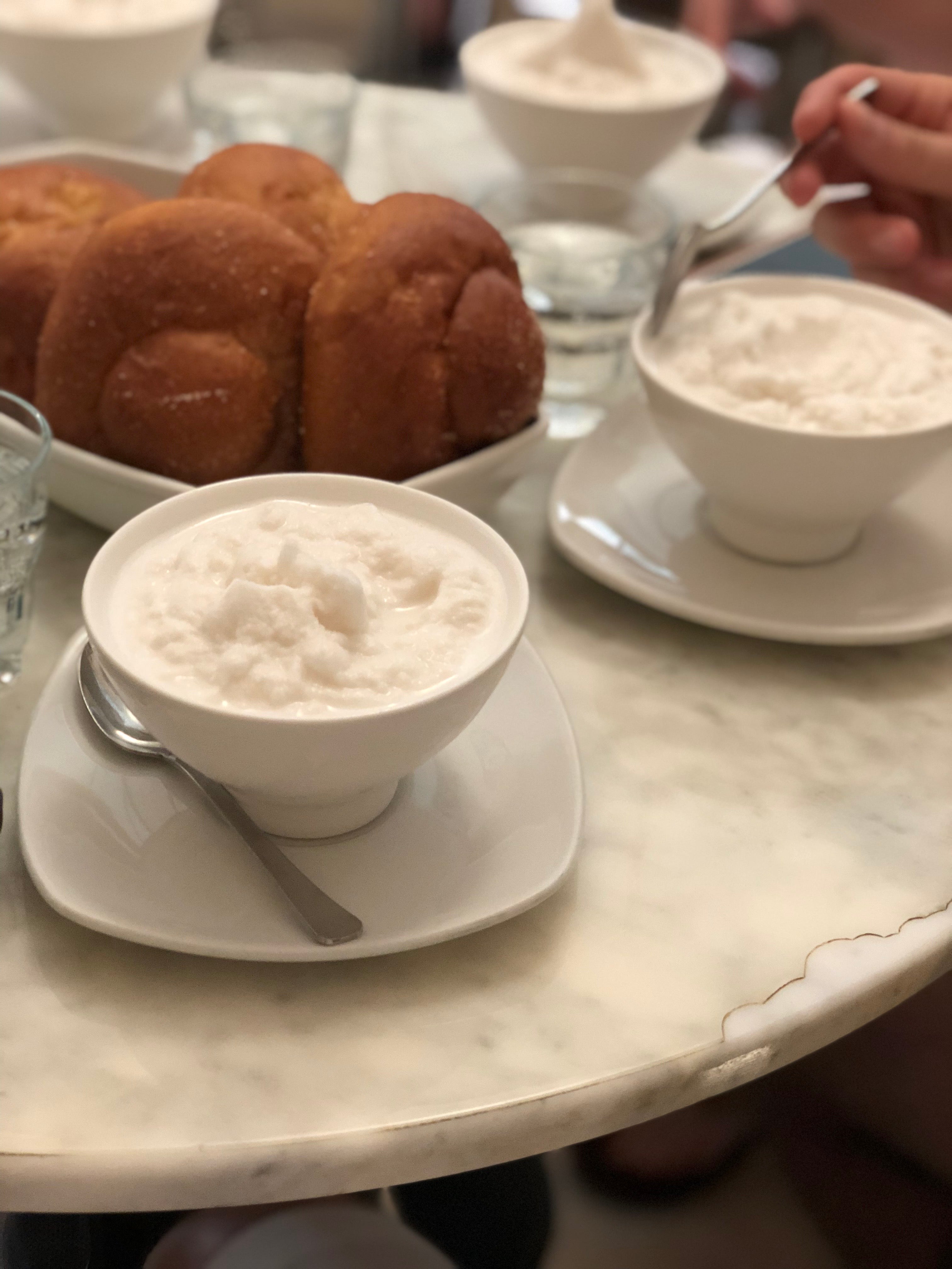 Creamy white almond granita and sugary brioche buns adorn a white marble table at Caffe Sicilia in Noto, Sicily.