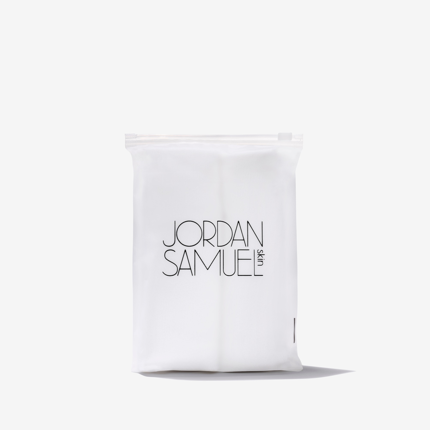 The Skincare Cloth product image - two white microfiber cloths rolled up side by side and placed in a clear resealable bag with a black Jordan Samuel Skin logo