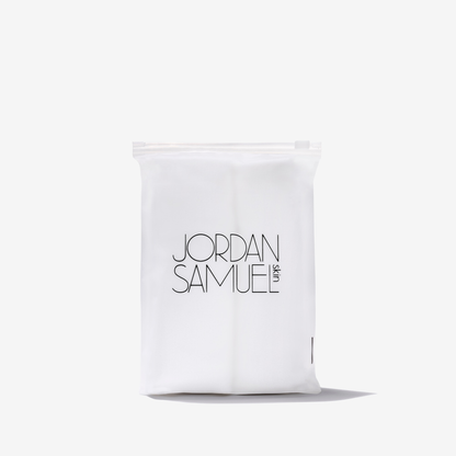 The Skincare Cloth product image - two white microfiber cloths rolled up side by side and placed in a clear resealable bag with a black Jordan Samuel Skin logo